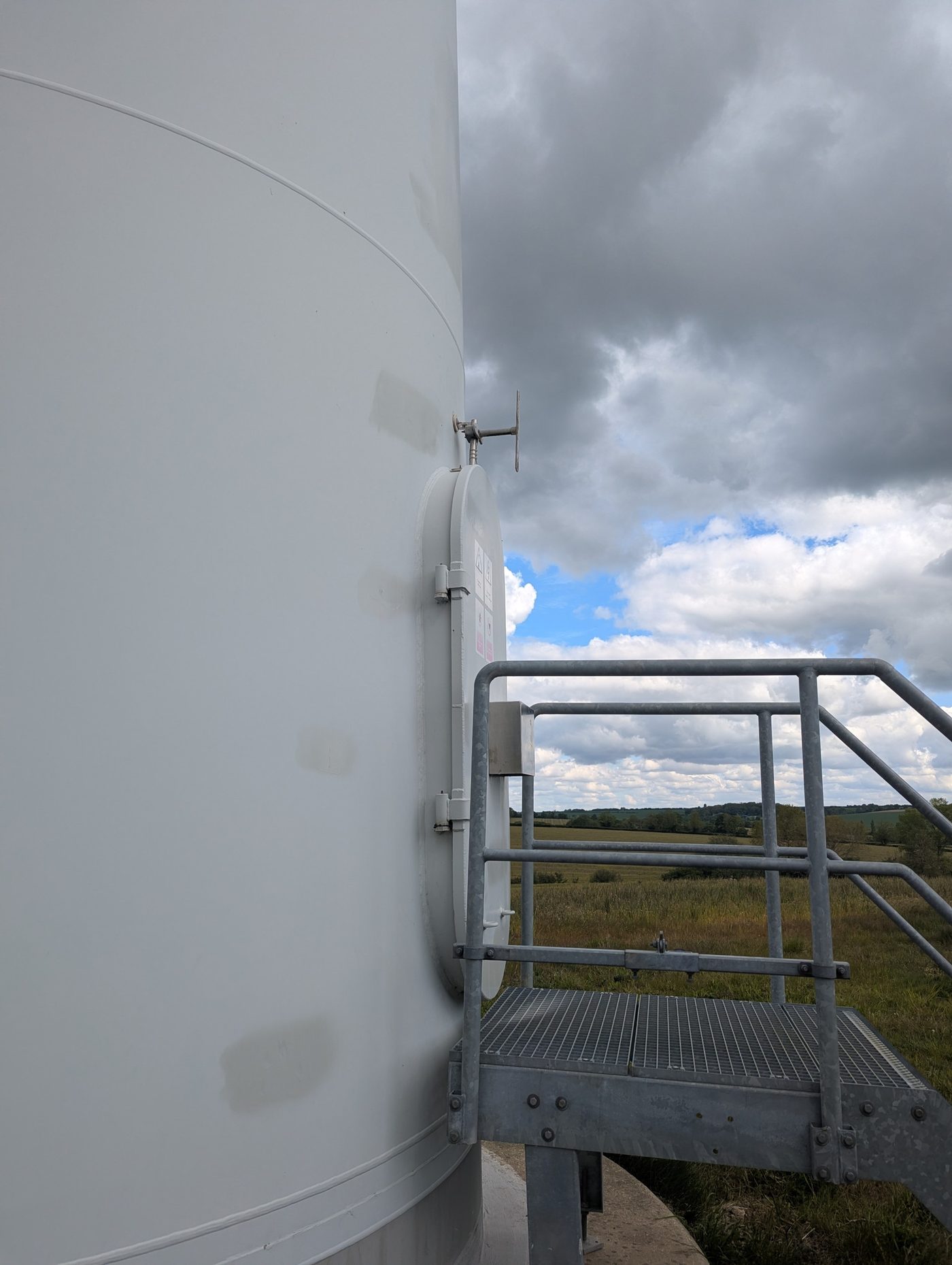 Wind turbine tower base with the door and access platform, showing the door surround welded into the white tower shell.